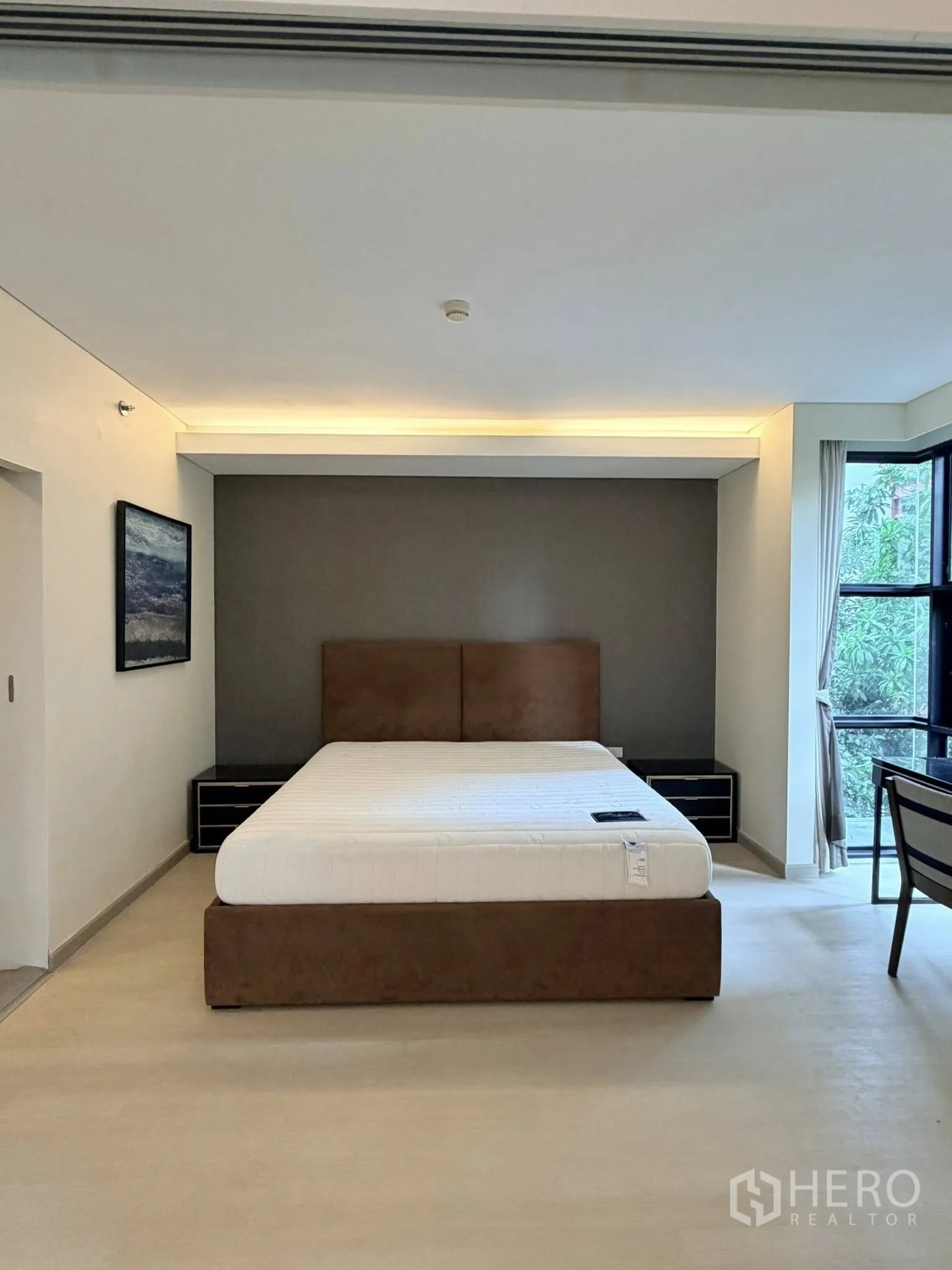 Condominium for rent in Watthana, Bangkok - Spacious bedroom with upholstered bed, bedside tables, and corner windows.