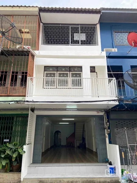 Shophouse for sale in Phra Khanong, Bangkok - Three-storey shophouse facade with front balcony, safety grilles and a wide roll-up storefront near BTS Bang Chak.