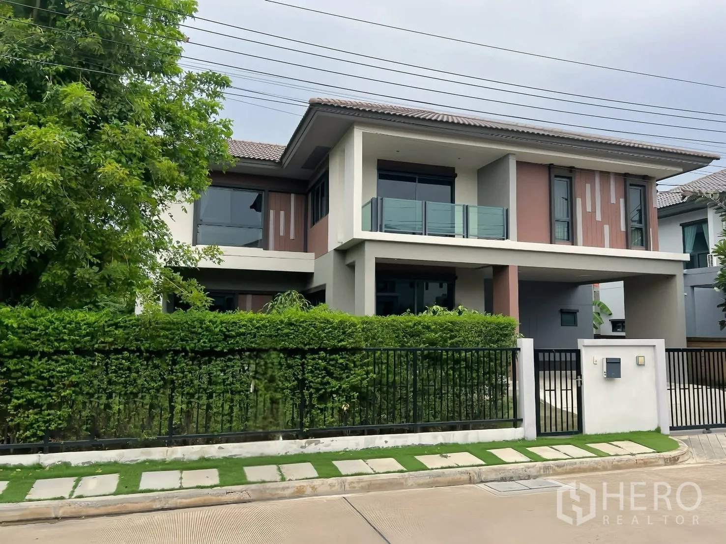 独栋房屋 for rent in Bang Phli, Samut Prakan - 两层现代独栋别墅外观，带阳台、车棚和绿篱大门。