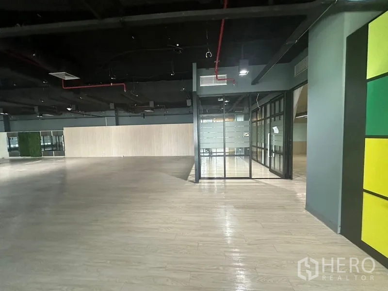 办公空间 出租在Bang Rak, Bangkok - 开放工位朝向成排磨砂玻璃房，天花设备外露。