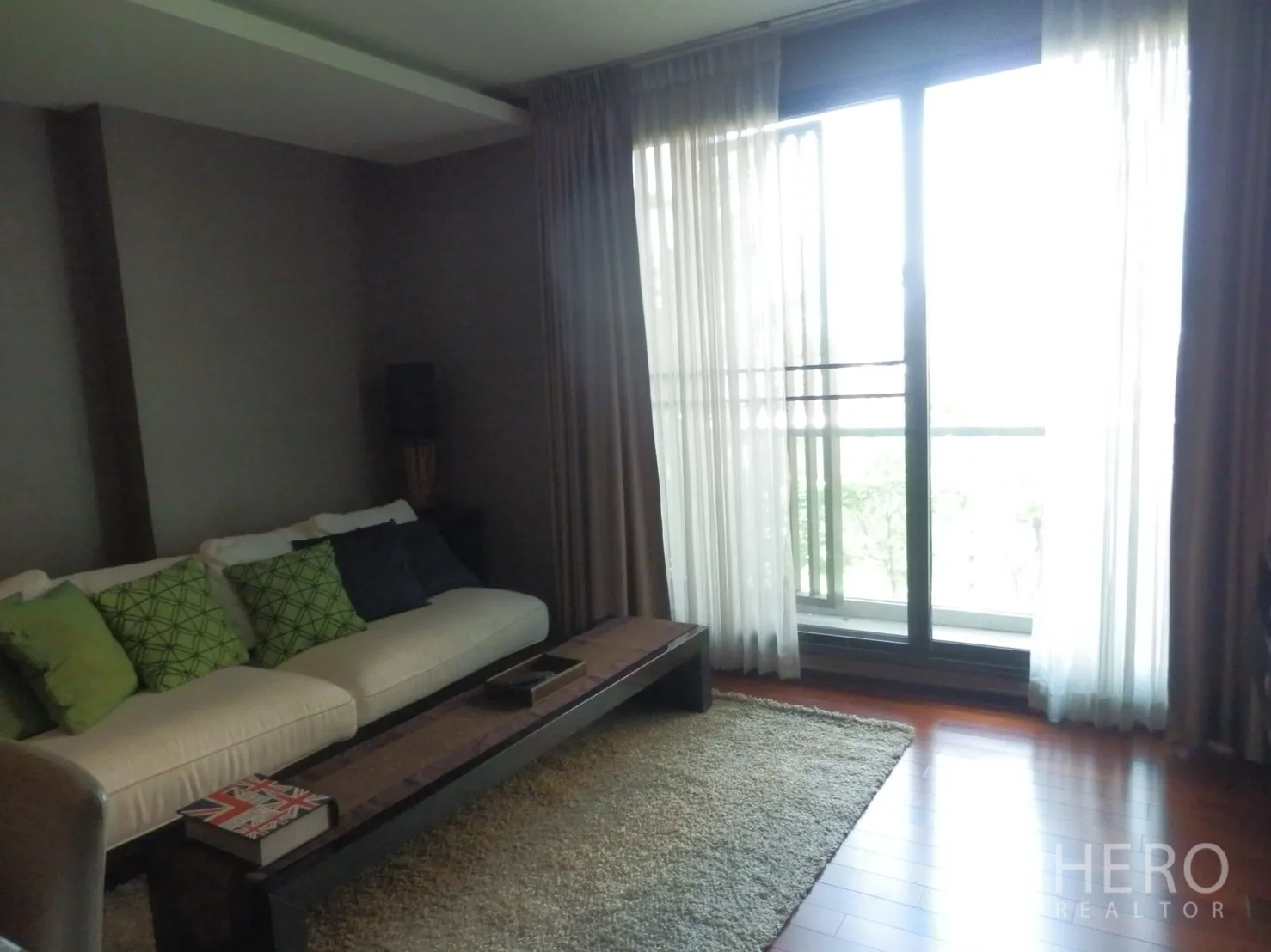 คอนโด ให้เช่าในWatthana, Bangkok - ห้องนั่งเล่นอบอุ่น โซฟา พรม และประตูกระจกบานเลื่อนออกสู่ระเบียง