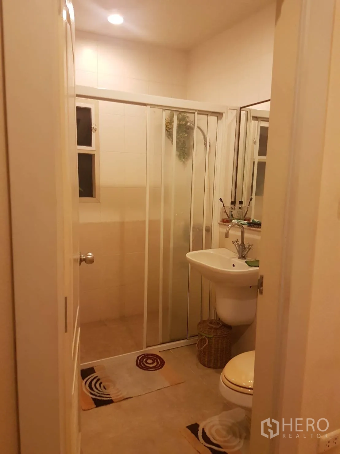 Detached House for sale in Lat Krabang, Bangkok - Bathroom with glass-enclosed shower, pedestal sink, mirror and small window.