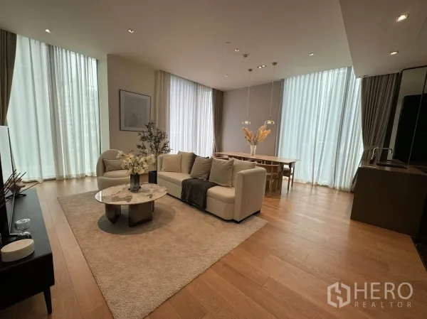 Condominium for rent in Pathum Wan, Bangkok - Open-plan living and dining area with floor-to-ceiling windows and warm wood floors.