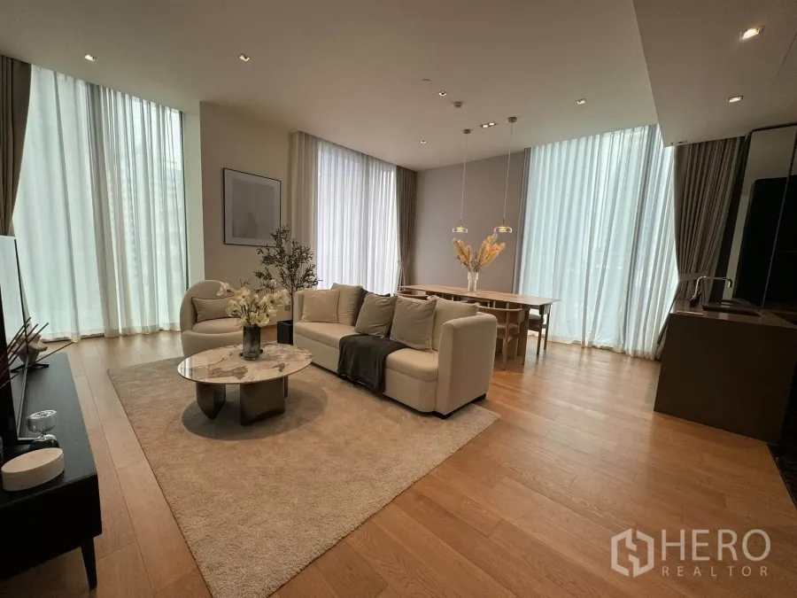 Condominium for rent in Pathum Wan, Bangkok - Open-plan living and dining area with floor-to-ceiling windows and warm wood floors.