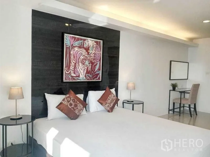 Condominium for rent in Khlong Toei, Bangkok - Bright bedroom with large bed, feature art wall, side tables and a small work desk.