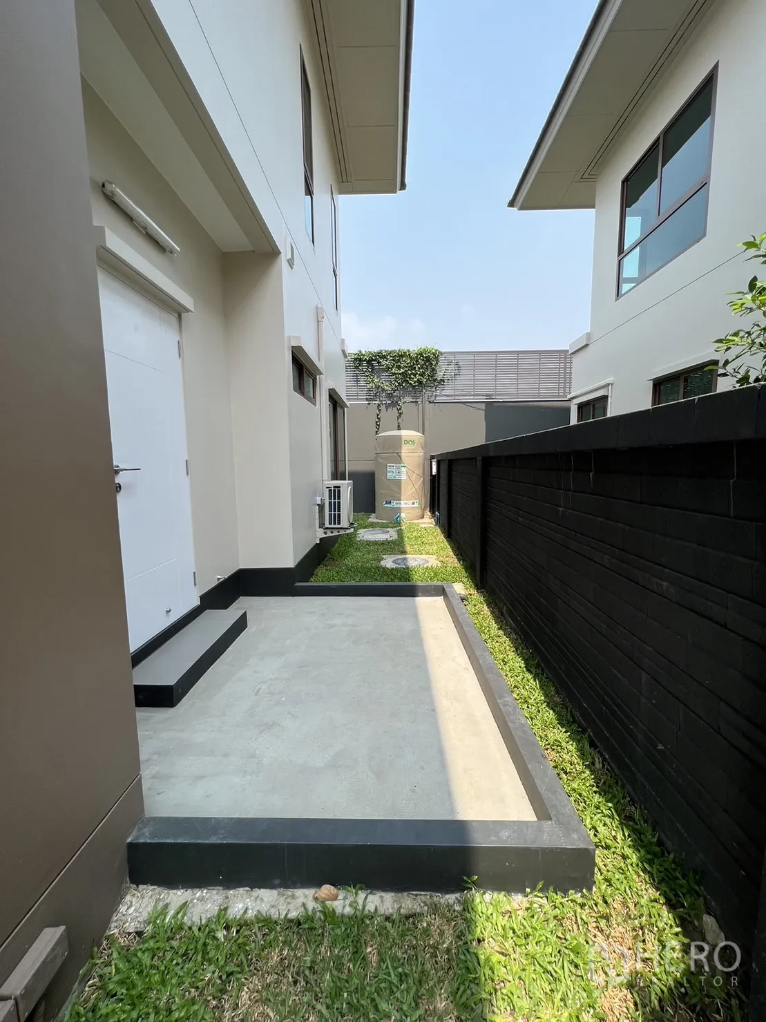 Detached House for rent in Bang Kapi, Bangkok - Side yard utility zone with water tank, lawn and service door.