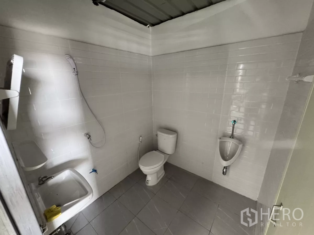 Warehouse for rent in Lam Luk Ka, Pathum Thani - Clean tiled restroom inside the warehouse with sink, toilet, urinal and shower.