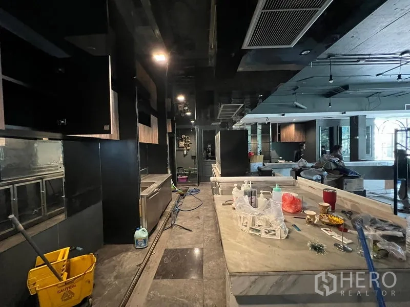 Retail Space for rent - Long marble-topped bar with dark fitted cabinetry in a dim, modern interior.