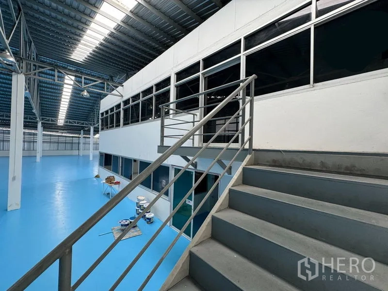 Warehouse for rent in Mueang Pathum Thani, Pathum Thani - Staircase leading to mezzanine offices overlooking the bright warehouse floor and skylit roof.