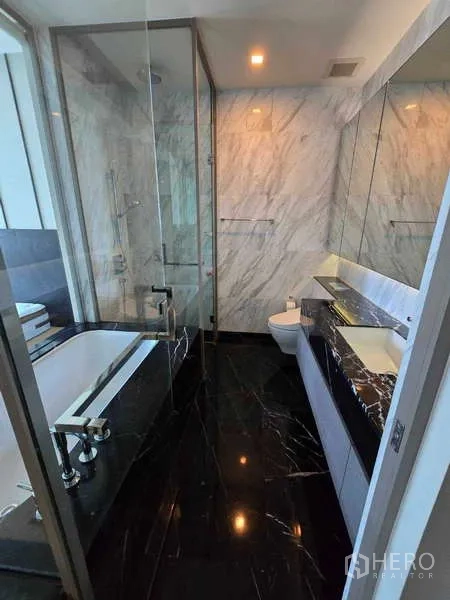 公寓 出租或出售在Bang Rak, Bangkok - 现代大理石浴室，玻璃淋浴间、浸泡浴缸与盥洗台。