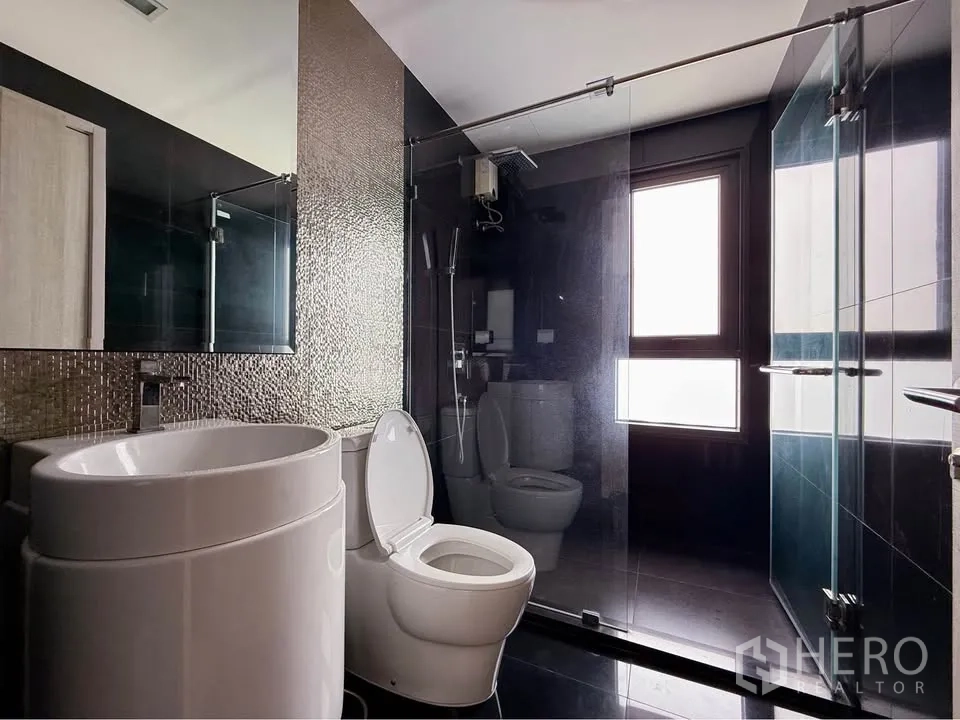 公寓 for rent in Khlong Toei, Bangkok - 现代浴室配马赛克墙、圆盆、马桶与玻璃淋浴间，靠近磨砂窗。