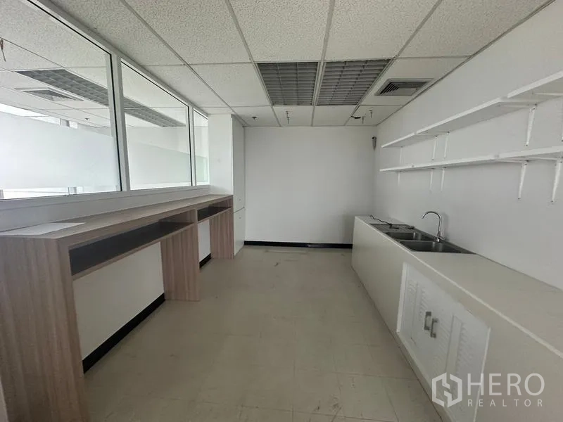 Office Space for rent - Another view of the office kitchenette featuring dual sinks, a long counter and wall shelves.