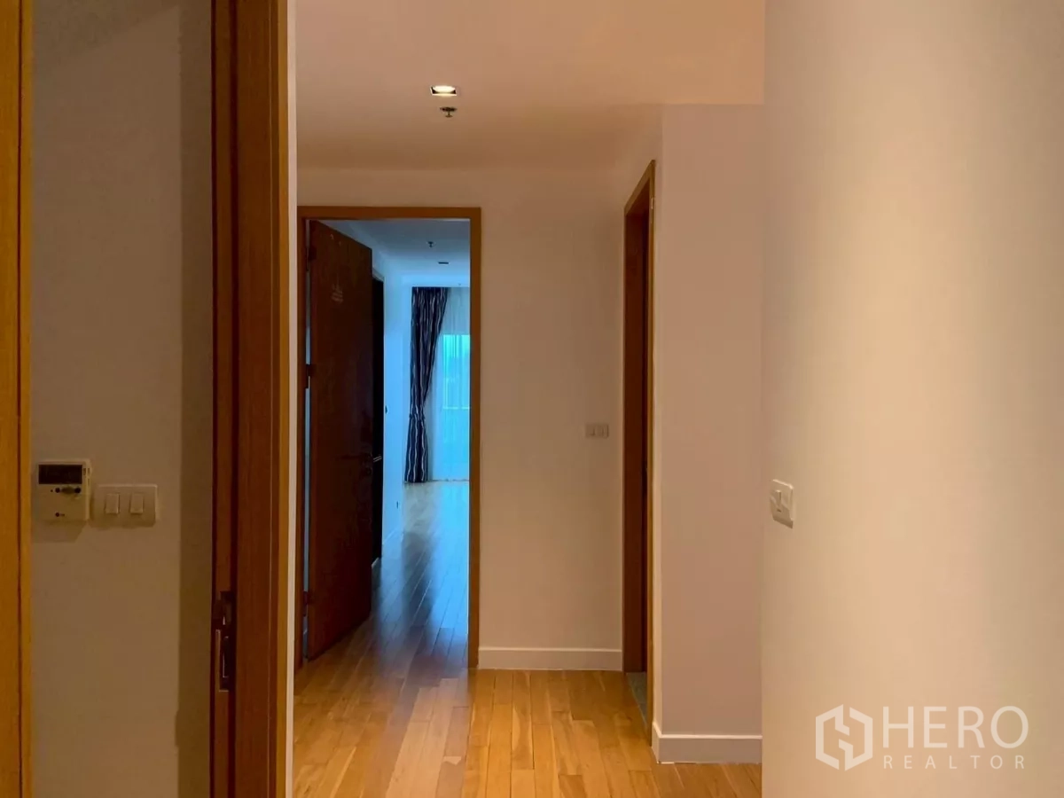 Condominium for rent in Khlong Toei, Bangkok - Hallway to bedrooms with wooden doors and natural light.