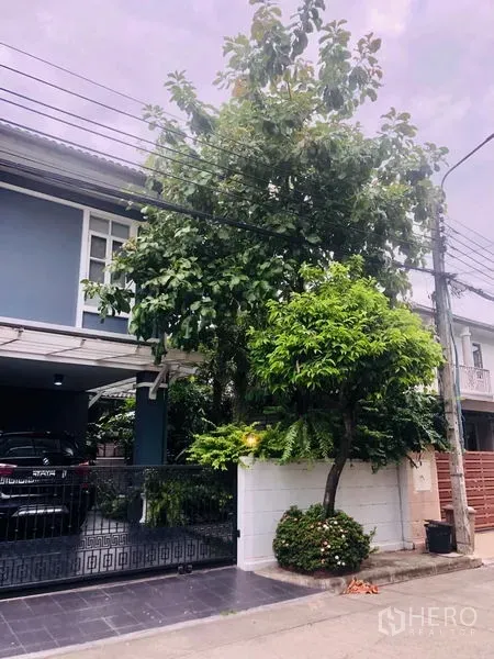 独立式住宅 出租在Bang Kapi, Bangkok - 房屋侧面景观，成荫大树与围墙，临安静的居民街道。