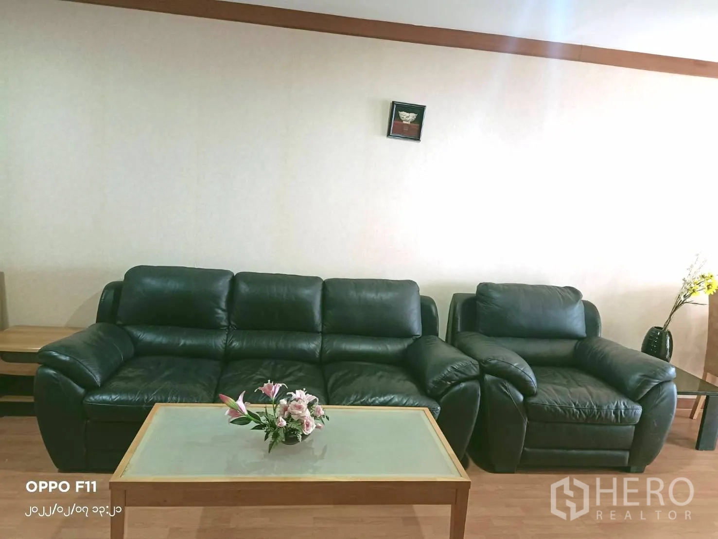 Condominium for rent in Khlong Toei, Bangkok - Cozy living room with black leather sofa set and glass coffee table against a neutral wall.