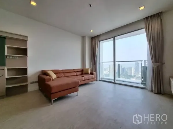 公寓 出租在Watthana, Bangkok - 采光充足的客厅，L形沙发与落地阳台门，俯瞰城市景观。