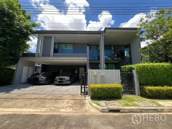 Detached House for rent in Bang Kapi, Bangkok - Modern two-storey detached house facade with gated entrance, landscaped hedges and covered parking for multiple cars.