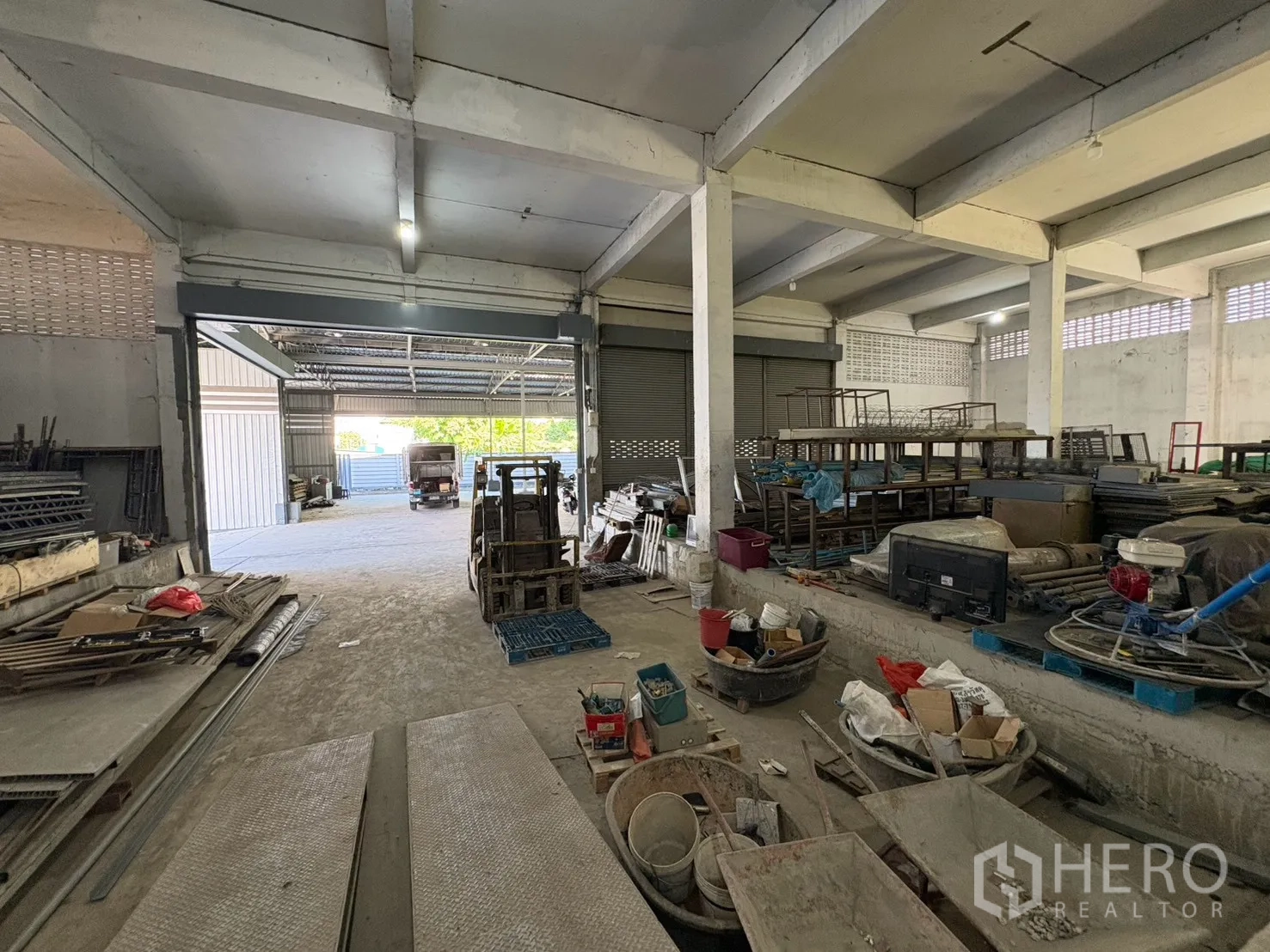 Warehouse for rent in Bang Na, Bangkok - Interior view toward an open roller door leading to a covered loading zone.