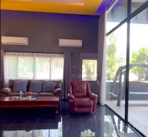 Detached House for sale in Bang Bua Thong, Nonthaburi - Lounge area with leather sofa set, armchair, split air-cons and floor-to-ceiling windows.