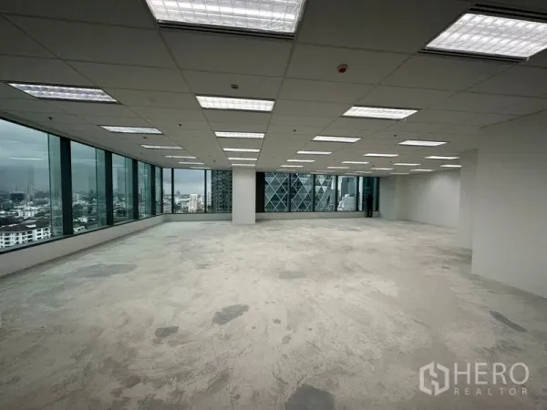 办公空间 出租 - 两侧整面玻璃与水泥地面的开放办公区，面向现代高楼。