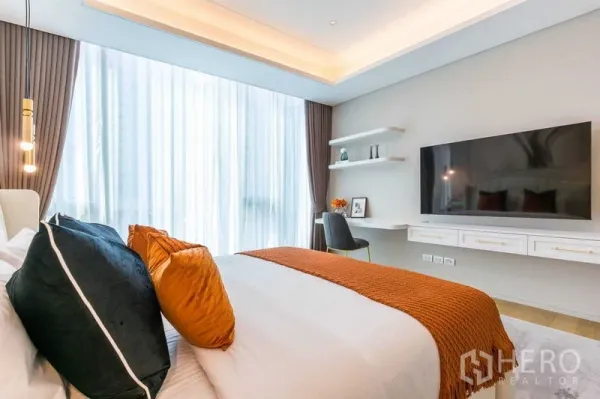 Condominium for sale in Pathum Wan, Bangkok - Bedroom view showing bed, wall-mounted TV and study desk beside large windows