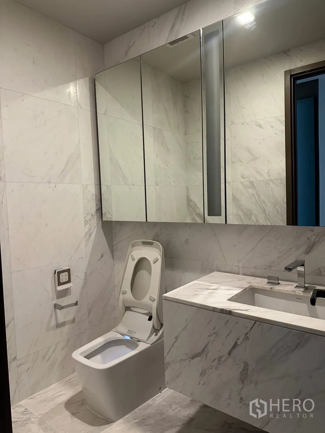 คอนโด for rent or sale in Watthana, Bangkok - ห้องน้ำโทนหินอ่อนสว่างพร้อมตู้กระจกและโถสุขภัณฑ์อัตโนมัติ.