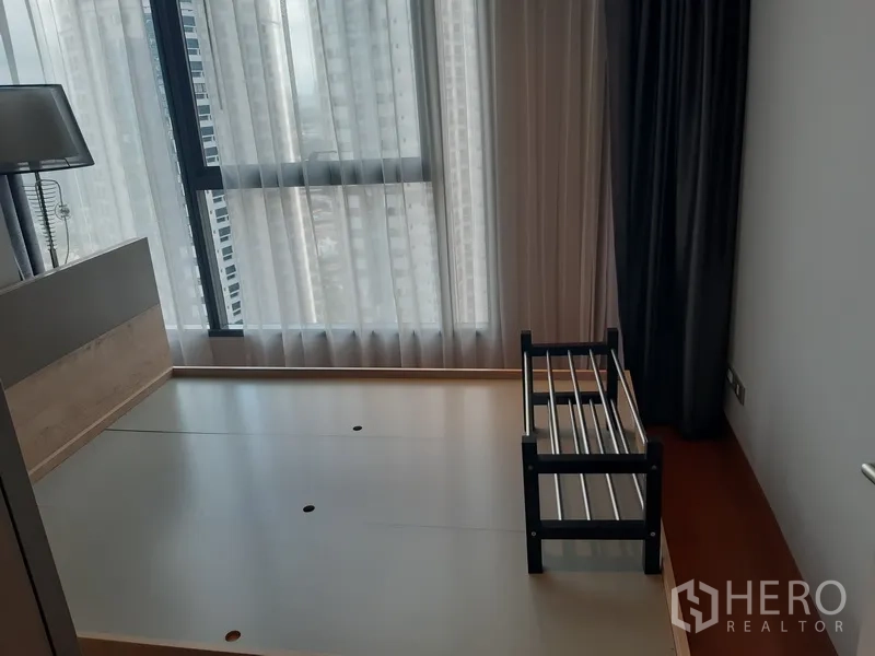Condominium for rent in Khlong Toei, Bangkok - Secondary bedroom with large window, platform bed frame and city outlook.