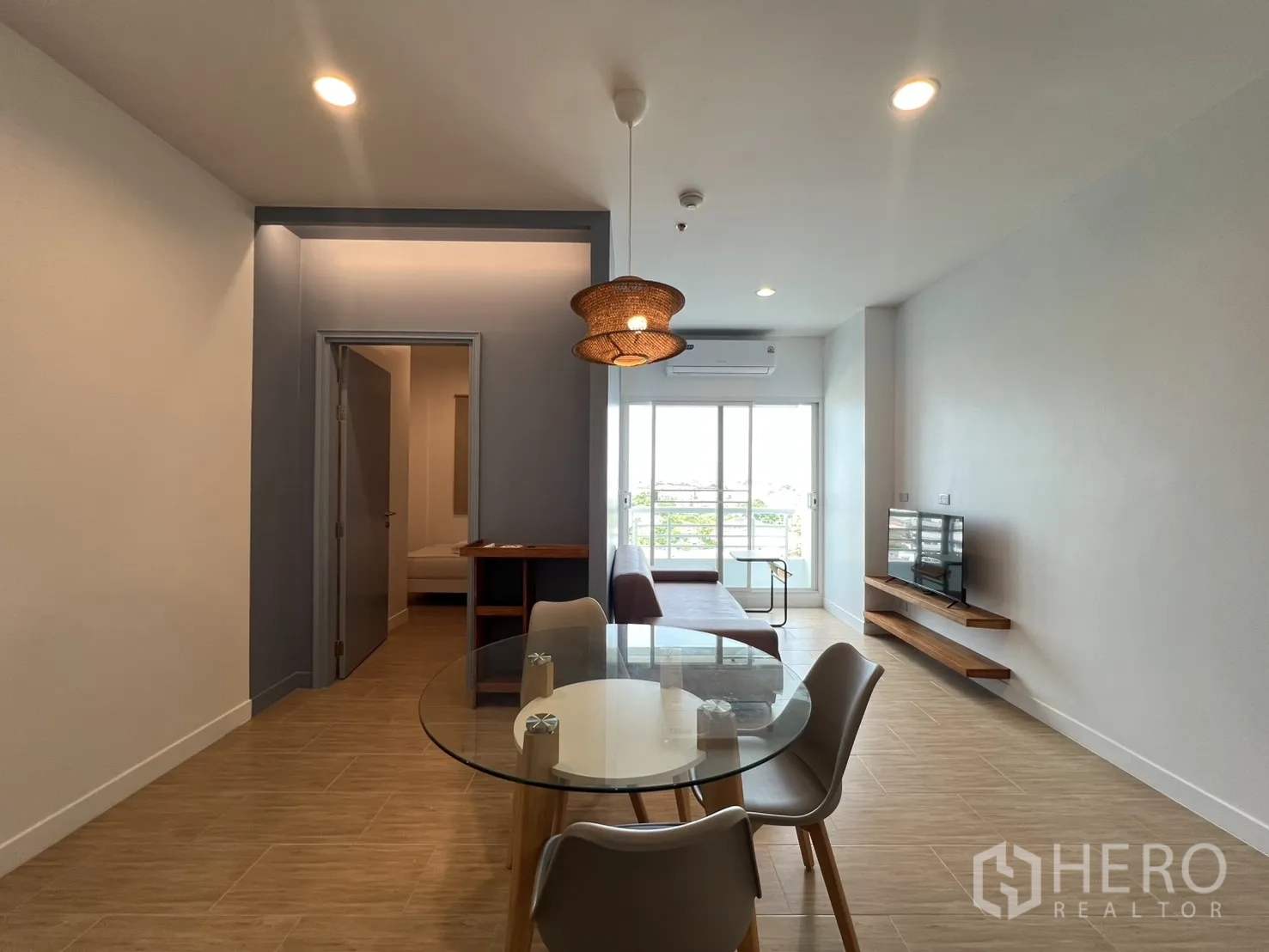 公寓 for rent in Bang Kapi, Bangkok - 开放式客餐厅，圆形玻璃餐桌、沙发、电视及通往阳台的推拉门。