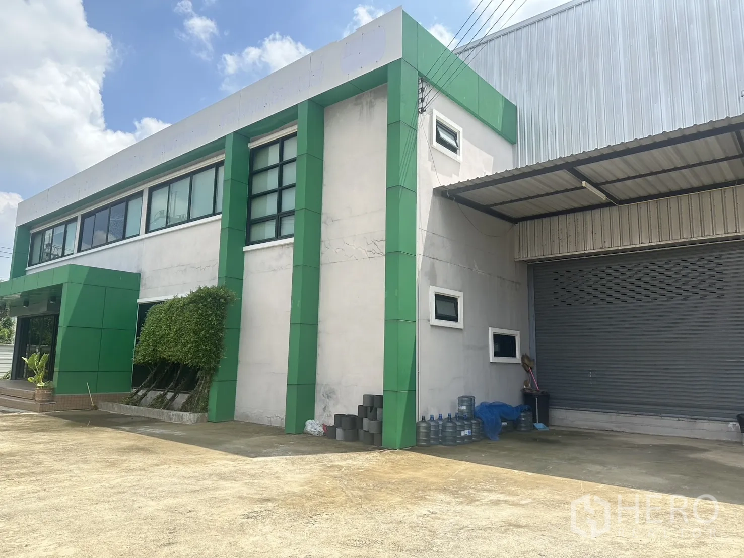 货栈 出售在Bang Len, Nakhon Pathom - 办公楼近景配灌木，旁有卷闸装卸门