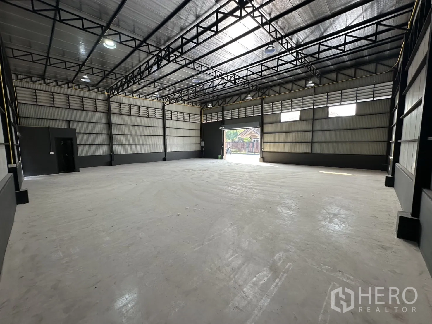 Warehouse for rent in Prawet, Bangkok - Spacious warehouse interior showing high steel truss roof, clerestory windows, bright lighting and a large front opening.