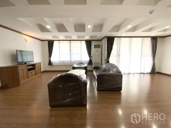 公寓 出租在Watthana, Bangkok - 明亮起居区，电视柜与沙发，木地板和大窗，位于瓦塔那区公寓。