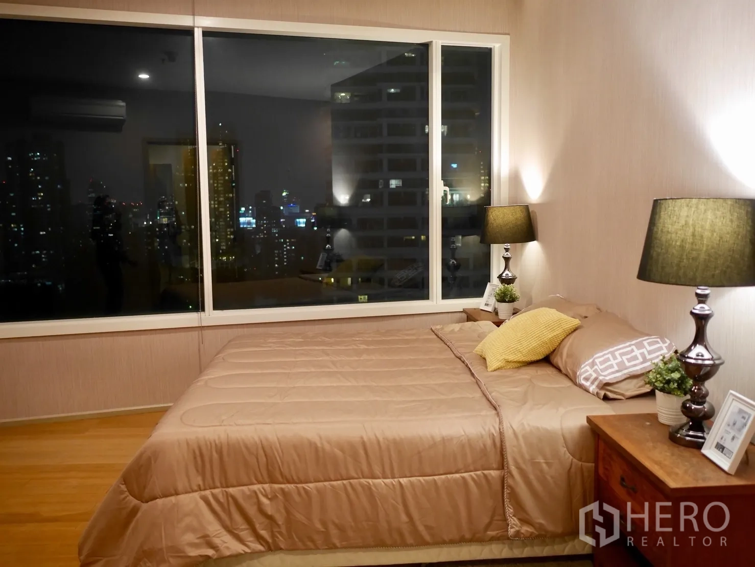 Condominium for rent in Watthana, Bangkok - Master bedroom with large window, night city view, bedside lamps and wood floors.