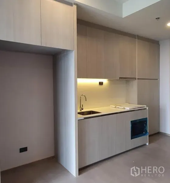 Condominium for sale in Khlong Toei, Bangkok - Compact light-wood pantry kitchen with ample cabinetry, sink and cooktop niche.