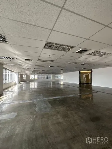 Office Space for rent in Pathum Wan, Bangkok - Open office level with glass entry, fluorescent lighting, ceiling vents, and wide corner windows.