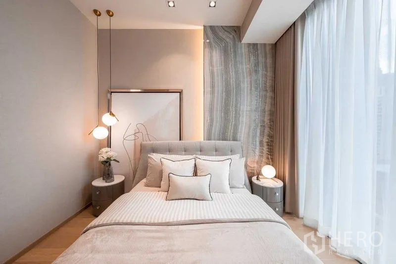Condominium for rent or sale in Pathum Wan, Bangkok - Bright bedroom with soft neutral bedding, pendant lamps and sheer curtains.