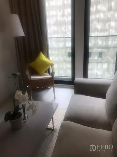 公寓 出租在Pathum Wan, Bangkok - 温馨客厅，布艺沙发、茶几、落地灯与大窗户，采光充足、面向城市景观。