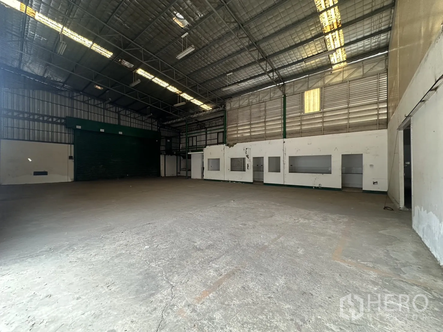 Warehouse for rent in Suan Luang, Bangkok - Wide open hall with insulated roof and green roller shutter for truck entry.