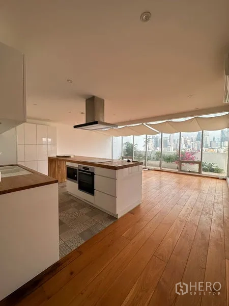 Condominium for rent in Khlong Toei, Bangkok - Kitchen and living area facing a terrace with panoramic city views and potted plants.