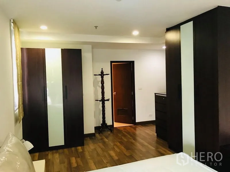 公寓 出租在Pathum Wan, Bangkok - 卧室储物区，衣柜、斗柜与通往浴室的门，木地板。