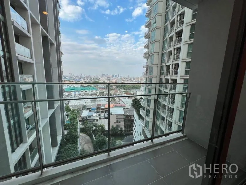公寓 出租在Watthana, Bangkok - 玻璃栏杆阳台，可观城市与邻近高楼景色。