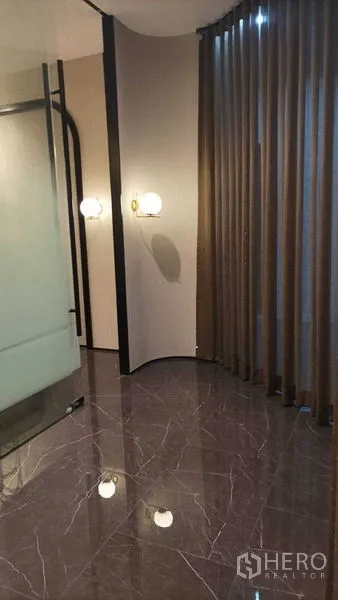 Retail Space for rent - Corner area with floor-to-ceiling curtains, wall sconces and glossy stone flooring.