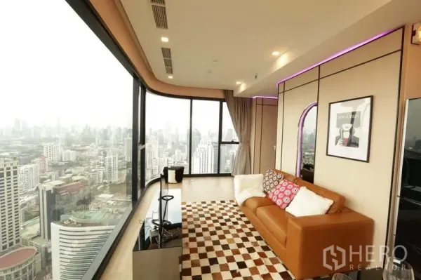 公寓 出租或出售在Watthana, Bangkok - 客厅配皮沙发与格纹地毯，环幕城市景观。