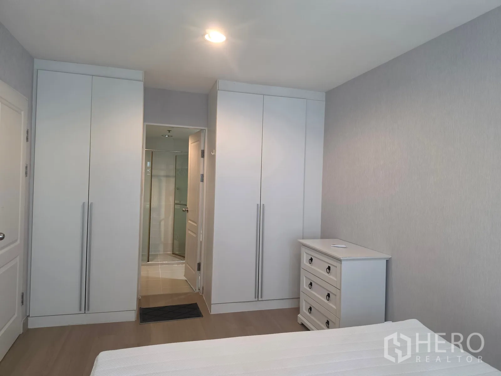 Condominium for rent in Huai Khwang, Bangkok - Bedroom wall with two built-in wardrobes and a dresser facing the ensuite.