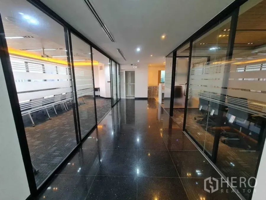 Office Space for rent - Sleek corridor with glass-walled meeting rooms and LED ceiling lights in a CBD building.