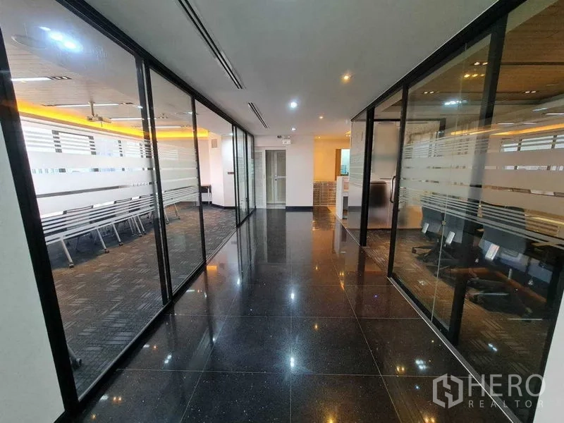 Office Space for rent - Sleek corridor with glass-walled meeting rooms and LED ceiling lights in a CBD building.