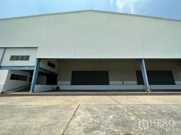 คลังสินค้า ให้เช่าในBang Phli, Samut Prakan - ชานโหลดมีหลังคากว้าง พร้อมประตูม้วนหลายจุดและเสาโครงเหล็กด้านหน้าโกดัง