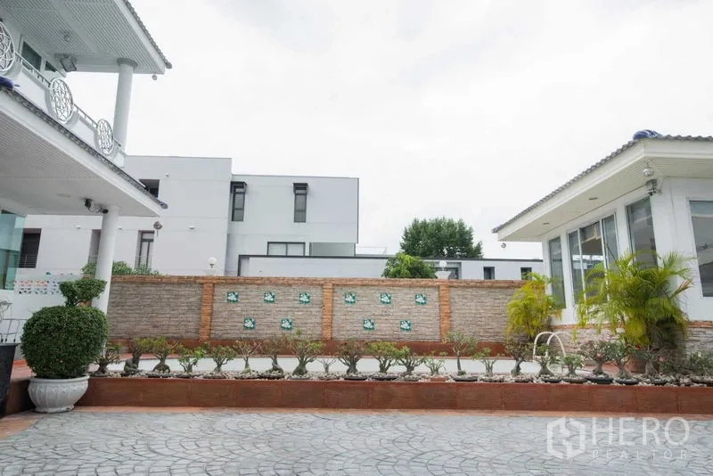 Detached House for rent or sale in Bang Kapi, Bangkok - Paved yard with brick feature wall and planters between main house and annex.