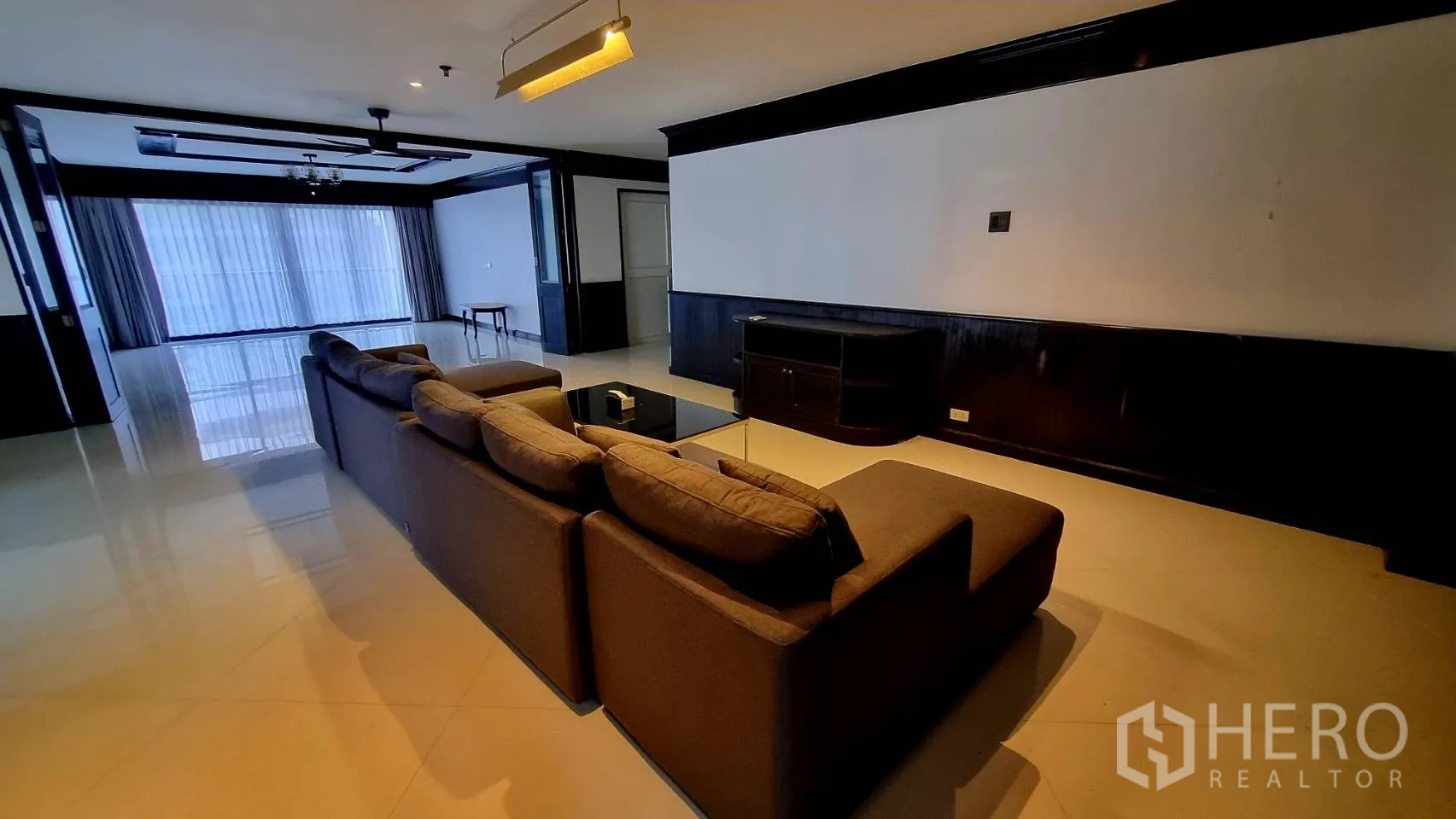 Condominium for rent in Watthana, Bangkok - Wide living room with sectional sofa, TV console and glossy floors.