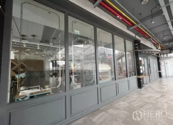 Retail Space for rent in Khlong Toei, Bangkok - Community mall corridor with long glass storefront and decorative frames.