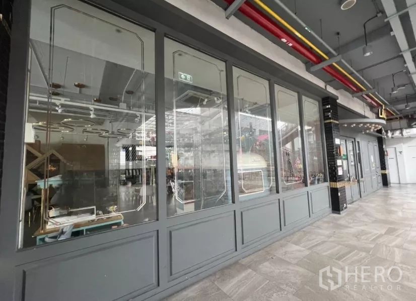 Retail Space for rent in Khlong Toei, Bangkok - Community mall corridor with long glass storefront and decorative frames.